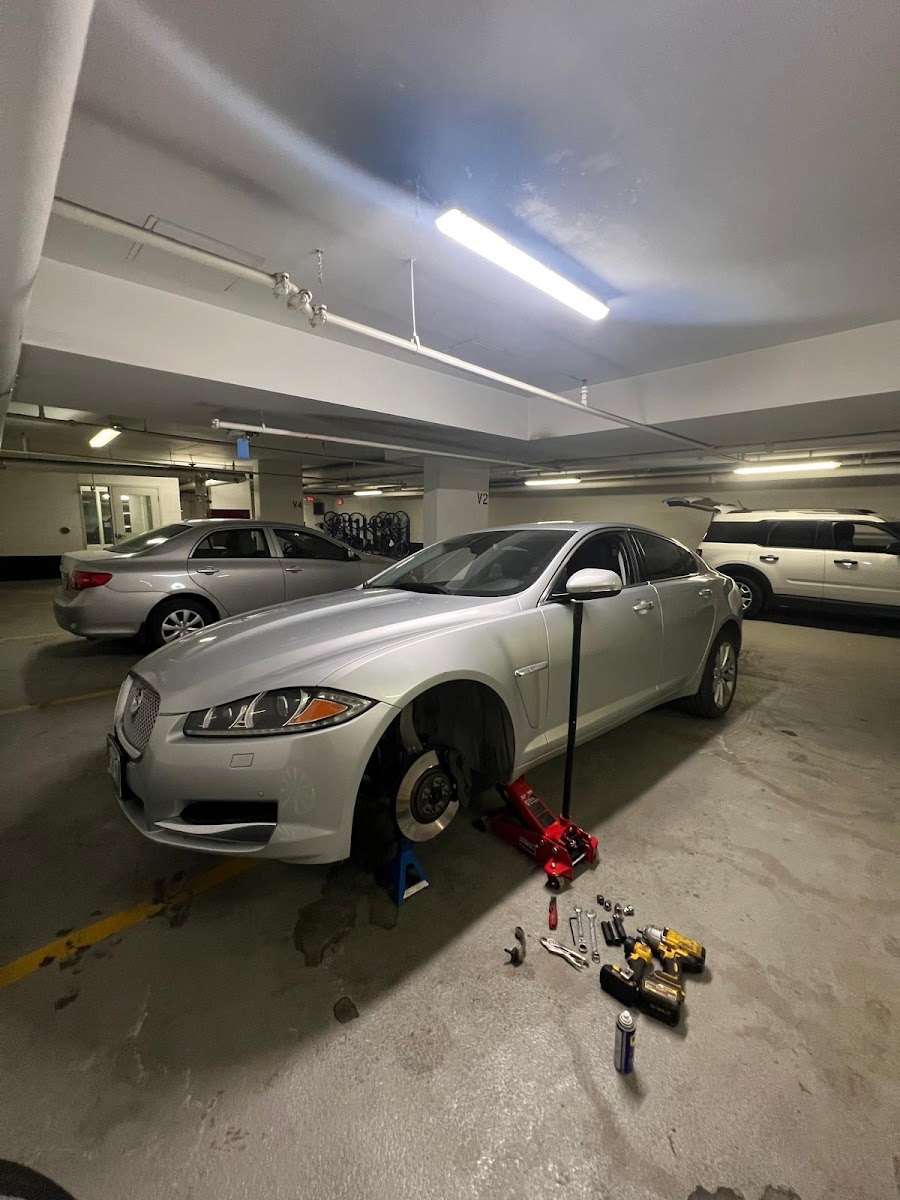 Mobile mechanic working on a vehicle in a parking garage