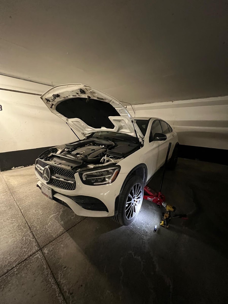 Mobile mechanic working under a vehicle hood